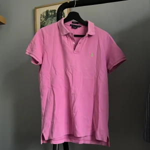 Rosa pikétröja från Ralph Lauren - Säljer en klassisk rosa pikétröja från Ralph Lauren i storlek M. Tröjan är kortärmad och tillverkad i 100% bomull med en broderad logotyp på bröstet. Perfekt för sommaren. Skick 8/10