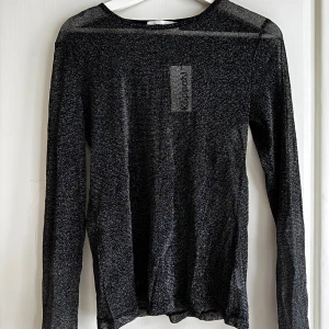 Svart glittrig tröja från Kappahl - Helt ny och oanvänd svart glittrig tröja från Kappahl i storlek M med prislapp kvar på.   Rensar ur min garderob från en hel del oanvända kläder🌼 Om du ser något mer i min profil som du gillar så skickar jag med det till dig också!😊 Fler kläder kommer! 