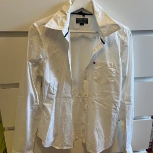 Vit skjorta från Ralph Lauren - Säljer en klassisk vit skjorta från Ralph Lauren i storlek L. Skjortan har en bröstficka och knappar framtill. 