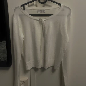 Vit kofta med knäppning - Säljer en stilren vit kofta från CC Fashion men är köpt på Missäy. Aldrig andvänd. Koftan har långa ärmar och en enkel hake framtill för stängning. Perfekt för att lägga till en touch av elegans till din outfit. Passar bra till både vardag och speciella tillfällen. Storlek L/XL men passar mig som är M men oxå min vän som är S/M.