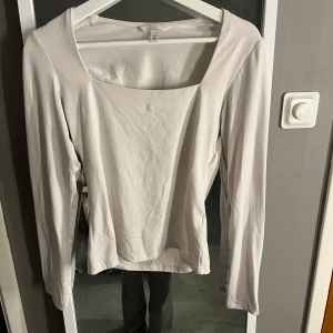Vit långärmad topp från H&M - Säljer en stilren vit långärmad topp från H&M. Toppen har en fyrkantig halsringning och är tillverkad i ett mjukt bomullsmaterial. Perfekt för en enkel och klassisk look.