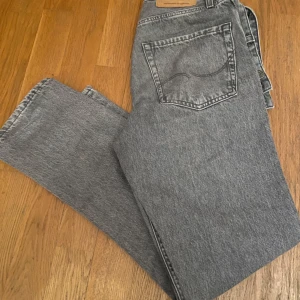 Grå jeans från Jack & Jones 27 30 - Säljer ett par grå jeans från Jack & Jones i modellen Loose/Chris stl 27 30. De har en avslappnad passform med klassisk femficksdesign och knappgylf. Perfekta för en casual look.💯💯