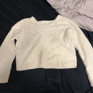 Beige stickad tröja från H&M - Säljer en mysig beige stickad tröja från H&M. Tröjan har en croppad design och långa ärmar, perfekt för kyligare dagar. Den är enkel och stilren, vilket gör den lätt att matcha med olika outfits. Perfekt för höst och vinter!