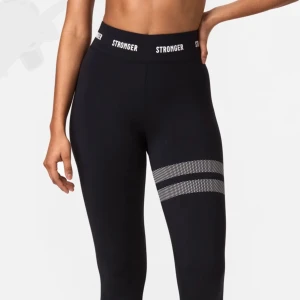 Svarta leggings från Stronger - Säljer dessa jätte sköna tights från stronger😍😍basic, snygga, bekväma, passar till träning💞inga större defekter, utom del texten inuti byxan som åkt av. Stronger texten och ränderna runt benet är helt kvar!👌👌Orginalpris: 799kr