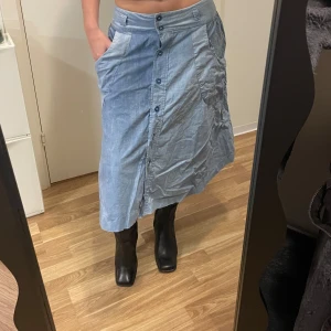 Blå denim/jeans kjol med knappar - Säljer en blå kjol med knappar framtill och stora fickor. Finns fickor. Finns inget märke eller storlek men jag är 160cm och när Xs