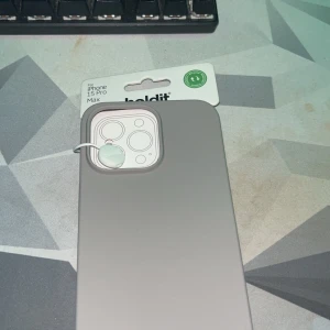 Grått mobilskal för iPhone 15 Pro Max från Holdit - Snyggt och stilrent grått mobilskal från Holdit, designat för iPhone 15 Pro Max. Skalet är gjort av ett mjukt material som ger ett bra grepp och skyddar din telefon mot repor och stötar. Perfekt för att hålla din mobil säker och stilren.