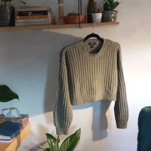 Grön stickad tröja från New Look - Säljer en snygg grön stickad tröja från New Look. Tröjan har en croppad design med långa ärmar och en ribbad struktur. Perfekt för en stilren och bekväm look.