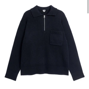 Mörkblå stickad tröja från Arket med dragkedja - Säljer en stilren mörkblå stickad tröja med dragkedja och krage. Tröjan har en praktisk bröstficka och långa ärmar. Perfekt för kyligare dagar. Storlek L