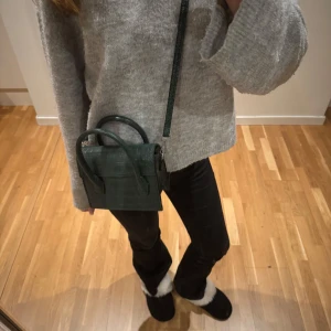 Grön axelväska i krokodilmönster - Snygg grön axelväska med krokodilmönster och justerbar axelrem, tjockare band medföljer. 