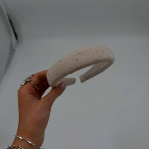 Beige diadem med pärlor - Elegant unikt beige diadem dekorerat med små pärlor. Gjort av second hand tyger. Perfekt för att ge en stilfull touch till din outfit. Passar bra för både vardag och speciella tillfällen.