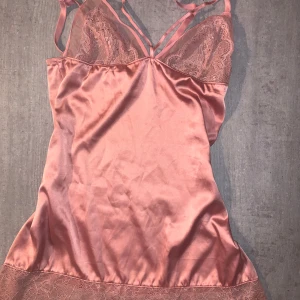 Rosa siden nattlinne  med spetsdetaljer - Elegant rosa nattlinne i siden med vackra spetsdetaljer vid bysten och nederkanten. Superfin design med tunna axelband och band vid bysten . Perfekt för en romantisk kväll eller speciella tillfällen. EJ ANVÄND PRIS KAN DISKUTERAS 