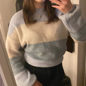  Stickad tröja från NA-KD - Säljer en mysig stickad tröja från NA-KD i storlek S. Tröjan har ett randigt mönster i ljusblått och beige med långa ärmar och ribbade kanter. Den är stor i storleken! 💙