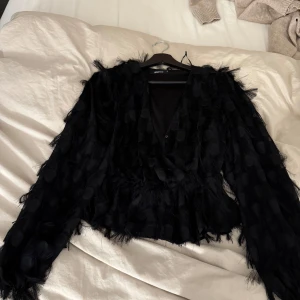 Jätte snygg svart blus! Passar bra med jeans,kjol eller shorts! - Snygg svart Blus från Gina Tricot med fransar och prickigt mönster. Blusen har en v-ringad design och långa ärmar, perfekt för en unik stil. Passar bra till både vardag och fest!