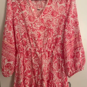 Rosa blommig klänning från Zara - Rosa blommig klänning från Zara med v-ringning och trekvartsärmar. Den är i ett lätt och luftigt material.