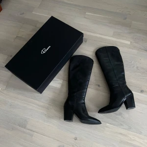 Svarta rizzostövlar med klack och dragkedja - Snygga svarta stövlar i skinn med en robust klack och dragkedja på sidan. Perfekta för en stilren look. De har en spetsig tå och kommer i en elegant förpackning. Nypris 2 699 kr 