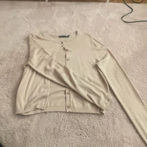 Beige kofta  - Säljer en stilren beige kofta från 157. Den har långa ärmar och knappar framtill. Den är helt ny i storlek S 