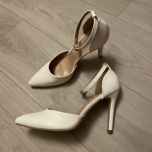 Vita klackskor  - Jättefina vita klackar med spetsig tå och smal klack. Kusterbar rem runt ankeln. Helt nya endast provade en gång, säljer då de är något stora🥰