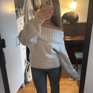 Beige offshoulder stickad tröja från Gina Tricot  - Säljer en mysig beige stickad tröja med offshoulder-design. Tröjan har långa ärmar och en bred ribbad kant upptill som ger en stilren look. Perfekt för kyligare dagar.