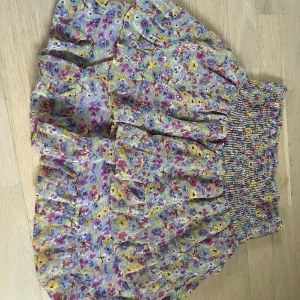 Blommig kjol från Pieces - Charmig blommig kjol från Pieces i härliga färger som lila, gul och rosa. Kjolen har en elastisk midja för bekväm passform och ett voluminöst fall. Perfekt för sommarens äventyr!