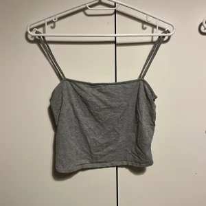 Grått linne från H&M - Säljer en enkel och stilren grå linnetopp med smala axelband. Perfekt för varma dagar eller som ett basplagg i garderoben. Toppen är i ett mjukt och bekvämt material.