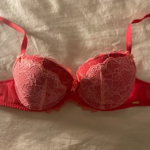 Rosa spets-bh - Säljer en snygg rosa bh från Dorina med vacker spetsdetalj och små rosetter. Bh:n har justerbara axelband och en bekväm passform. Perfekt för att känna sig extra fin! 💖