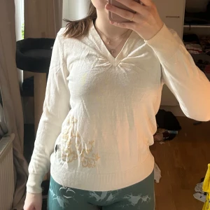 Vit tröja med mönster - Säljer denna tröja då jag inte använder den och har många liknande. Den har ett gulaktigt mönster och detalj kring nacken. 