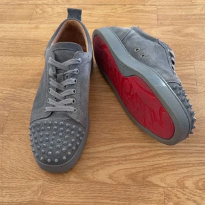 Christian Louboutin junior spikes  - Gråa Louboutin med fräscha röda sulor. Skorna är i mycket bra skick och knappt använda. Storlek 45 men passar även 44. Tveka inte på att höra av dig om du har några funderingar eller vill ha fler bilder. kom med prisförslag så kan vi diskutera vid en snabb affär. Box och dustbag medkommer 