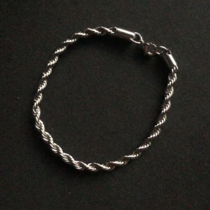 Silverfärgat tvinnat armband - Snyggt silverfärgat armband med tvinnad design. Perfekt för att ge en stilren touch till din outfit. Armbandet har en enkel låsning som gör det lätt att ta på och av.