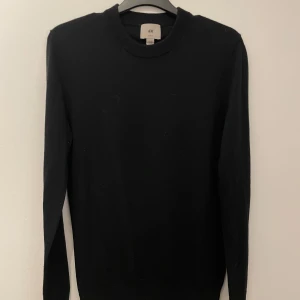 Svart tröja från H&M - Säljer en stilren svart tröja från H&M i slim fit. Perfekt för en minimalistisk look. Tröjan har långa ärmar och en klassisk rund halsringning. Passar bra till både jeans och chinos. Skriv om du har funderingar och priset är inte hugget i sten!
