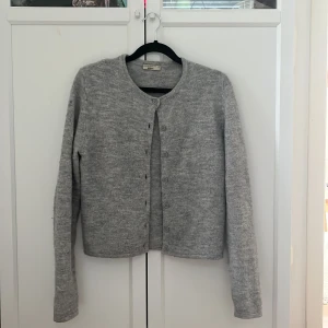 Grå kofta från Gina Tricot - Säljer en stilren grå kofta från Gina Tricot i storlek XS. Koftan har långa ärmar och knappar framtill, perfekt för lager-på-lager under kyligare dagar. Den är tillverkad i ett mjukt material som ger en bekväm passform. Kom privat för fler bilder💕