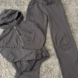 Grå hoodie och byxor från BikBok - Säljer ett set med en grå hoodie och matchande lågmidjade byxor från BikBok. Byxorna har en bekväm resår i midjan med snören. Perfekt för mysiga dagar hemma eller en avslappnad dag ute. Knappt använda🩶