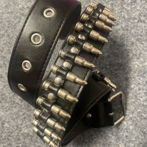 Svart bälte med nitar - Coolt svart bälte med silverfärgade nitar i form av kulor. Bältet har även silverfärgade öljetter och ett spänne i metall. Perfekt för att ge en edgy look till din outfit.