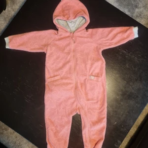 Fin fleeceoverall / fleecedress med stjärnmönster. Från Cubus - Fin, mjuk och mysig fleeceoverall / fleecedress med stjärnmönster. Från Cubus  Fint skick  2 små fickor.  Dragkedja hela vägen ner till ena foten.  Luva med toffs.  Storlek 92