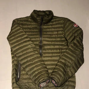 Olivgrön pufferjacka från Colmar - Säljer en olivgrön pufferjacka från Colmar med dragkedja framtill och två sidofickor med dragkedjor. Jackan har en hög krage och är perfekt för kyligare dagar. Den quiltade designen ger en stilren look. Pris kan diskuteras vid snabb affär!