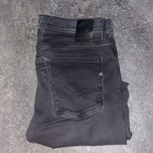  Replay jeans - Snygga svarta jeans från Replay i modellen Anbass. De har en modern slim passform och är tillverkade i Hyperflex-material för extra komfort och stretch. Perfekta för en stilren look med klassiska femficksdetaljer och knappgylf.  Mvh luxury 