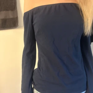 Mörkblå offshoulder topp - Säljer en stilren mörkblå offshoulder topp med långa ärmar. Perfekt för en trendig look. Toppen är i ett mjukt material som sitter bekvämt. Storlek S. Från nelly 