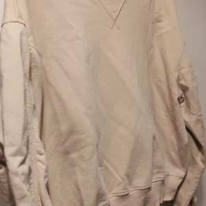Beige sweatshirt från Carin Wester - Säljer en stilren beige sweatshirt från Carin Wester i storlek M. Tröjan har långa ärmar och en ribbad krage. Den har en diskret dragkedja på sidan för extra stil och funktionalitet. Perfekt för en avslappnad look.