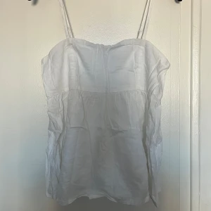Vit linnetopp från BikBok - Säljer en vit linnetopp från BikBok med smala axelband och en luftig passform. Toppen är perfekt för varma dagar och har en enkel design som gör den lätt att matcha med olika outfits. Passar även på M. 💞