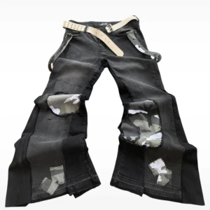 Svarta jeans med camo-detaljer - Unika svarta jeans med camo-lappar och slitna detaljer. Byxorna har en loose passform. Perfekta för en edgy stil.