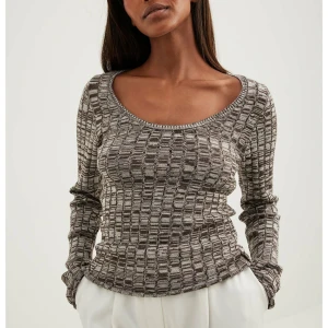 Gråmönstrad ribbad tröja från NA-KD - Säljer en stilren gråmönstrad tröja från NA-KD. Tröjan har en ribbad struktur och en rundad halsringning. Perfekt för en avslappnad look. Använd en gång