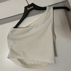 Vit oneshoulder topp från Shein - Snygg vit oneshoulder topp från Shein i ribbat material. Perfekt för en trendig look med sin asymmetriska design. Passar bra till både jeans och kjol.