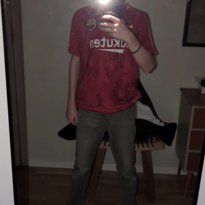 Röd FC Barcelona fotbollströja från Nike - Säljer en röd FC Barcelona fotbollströja från Nike med korta ärmar och Dri-FIT-teknologi. Tröjan har klubbens emblem på bröstet och sponsorlogga på framsidan. Perfekt för fans av laget!