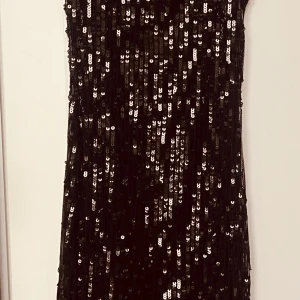 Svart paljettklänning - Snygg svart paljettklänning. Perfekt för en kväll ute eller en fest. Klänningen har en figurnära passform och är ärmlös, vilket ger en elegant look.
