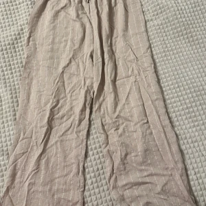 Beige linnebyxor med ränder - Säljer ett par bekväma beige linnebyxor med diskreta ränder. Perfekta för en avslappnad stil. Byxorna har en loose passform och är idealiska för varma dagar.