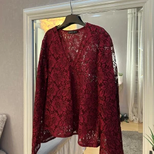Vinröd spetsblus - Snygg vinröd blus i spets från Stockh LM med v-ringning. Köpt från MQ. Aldrig använd så den är i nyskick