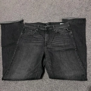 Grå jeans från Replay - Snygga grå jeans från Replay med klassisk femficksdesign. De har en rak passform och är perfekta för en avslappnad stil. Märkeslappen på baksidan ger en extra touch av stil.