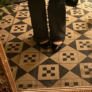 Svarta ballerinaskor med rem - Snygga svarta ballerinaskor i lack med justerbar rem runt ankeln. Perfekta för en stilren look.