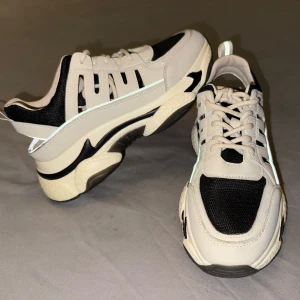 Svart beiga sneakers NA-KD - Snygga svart beiga sneakers från NA-KD med en chunky sula och snörning. Skorna har en modern design med kontrasterande svarta och vita paneler, perfekt för en trendig look.