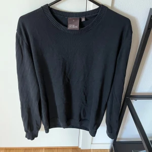 Svart tröja från Oscar Jacobson - Snygg svart tröja från Oscar Jacobson, tillverkad i Italien. Tröjan har en klassisk design med rund hals och ribbade kanter. Stickad tröja med skön passform. Använt den fåtal gånger. Ny pris: 1200kr. Pris kan diskuteras.