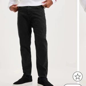 Svarta jeansbyxor - Snygga svarta jeansbyxor med en straight passform. Perfekta för en stilren look. De har klassiska fem fickor och en knappgylf.